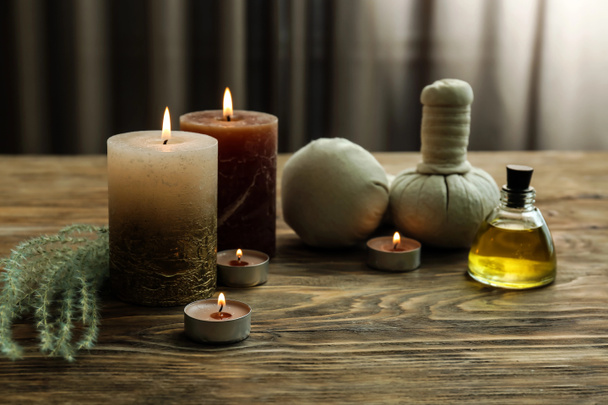 Krásné lázeňské složení s hořící svíčky, esenciální oleje a bylinné sáčky na dřevěný stůl - Fotografie, Obrázek