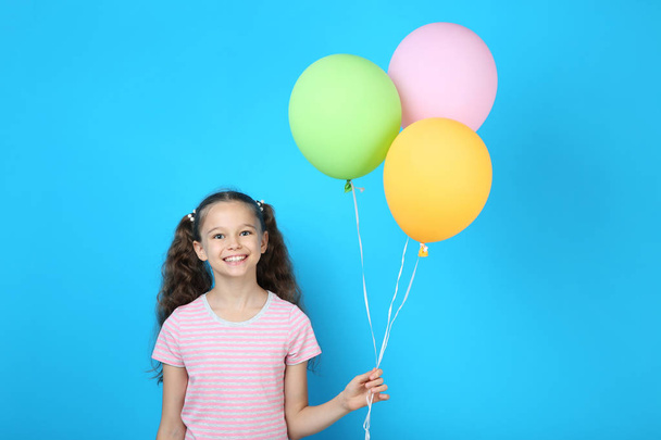 Cute young girl with colored balloons on blue background - Foto, afbeelding