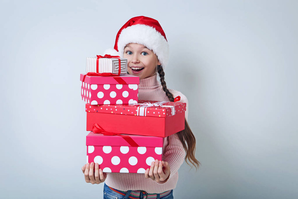 Young beautiful girl holding in hands gift boxes on grey background - 写真・画像