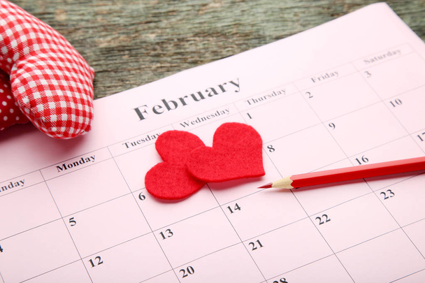 Red hearts with february calendar and pencil on wooden table - Valokuva, kuva