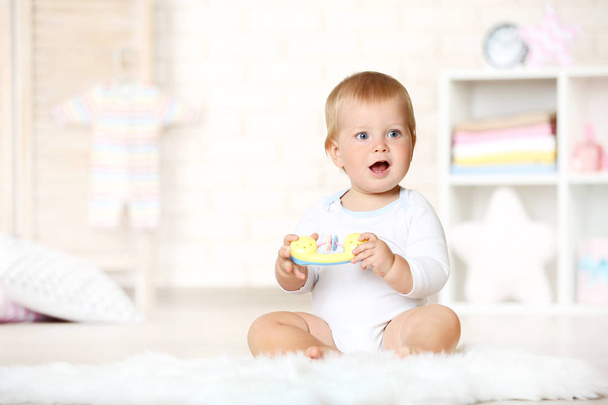 Baby boy with toys sitting on carpet at home - Fotó, kép