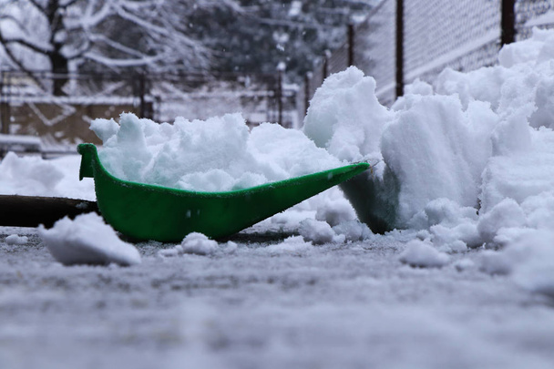 A téli időszakban erősödik. Egy ember, műanyag lapáttal a shoveling hó, autóbeálló, otthon a. Még hó és Havazik. - Fotó, kép