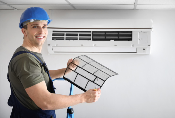 Electrician repairing air conditioner indoors - Fotoğraf, Görsel
