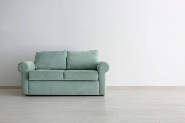 Удобный диван возле белой стены в номере - Фото, изображение