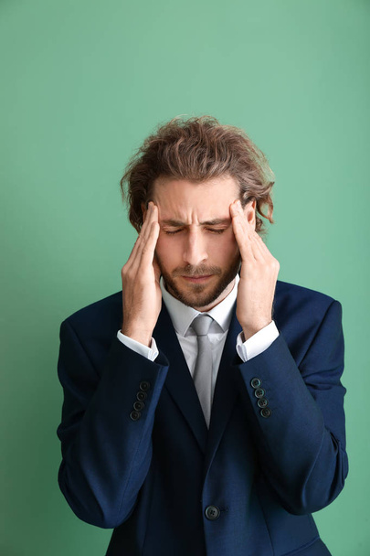 Jonge zakenman lijden aan hoofdpijn op kleur achtergrond - Foto, afbeelding
