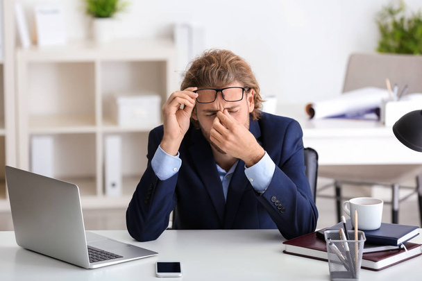 jonge zakenman lijden hoofdpijn in office - Foto, afbeelding