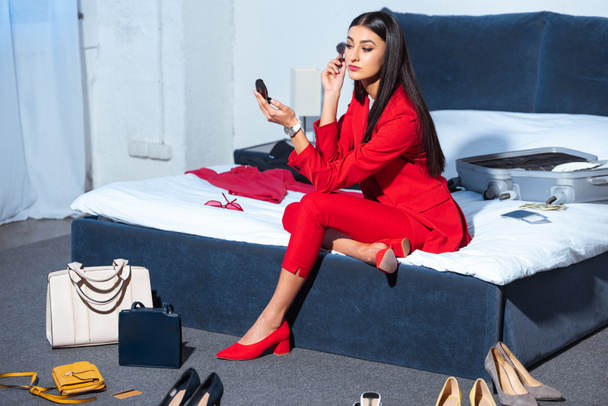 atractiva mujer joven con estilo sentado en la cama y la aplicación de maquillaje
  - Foto, Imagen