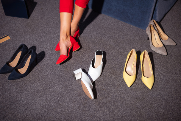 low section of girl in stylish red shoes and various fashionable footwear on carpet - Photo, Image