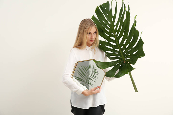 Retrato de mujer hermosa con hoja tropical verde y espejo sobre fondo blanco
 - Foto, Imagen