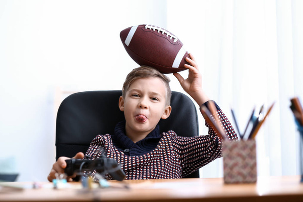 Cute boy with rugby ball playing video game at home - Foto, immagini