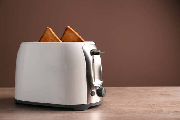 Toaster mit Brotscheiben auf dem Tisch vor farbigem Hintergrund - Foto, Bild
