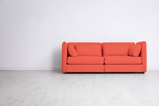 Stylish sofa near wall, space for text. Interior design with living coral color  - Photo, image