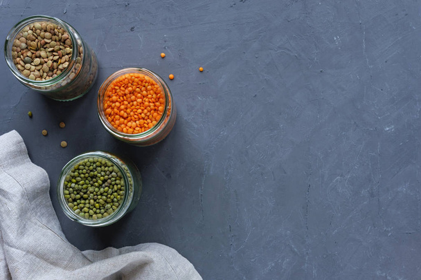 Três jarros de lentilhas e ervilhas sobre um fundo azul manchado com espaço de cópia visto de cima rico em fibras proteicas e vitaminas
 - Foto, Imagem