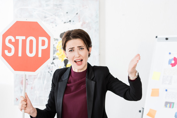 mujer de negocios enojada sosteniendo stop signo y gritando en la oficina
 - Foto, Imagen