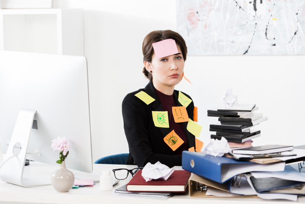 sconvolto attraente donna d'affari seduto con adesivi sul viso e vestiti in ufficio, guardando la fotocamera
 - Foto, immagini