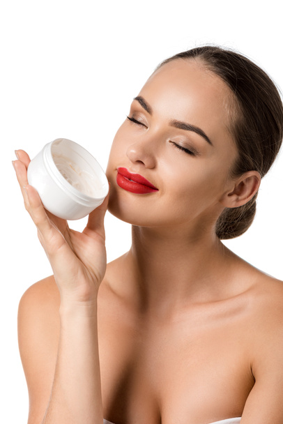 attractive girl with red lips and closed eyes smiling and holding jar with face cream isolated on white - Photo, Image
