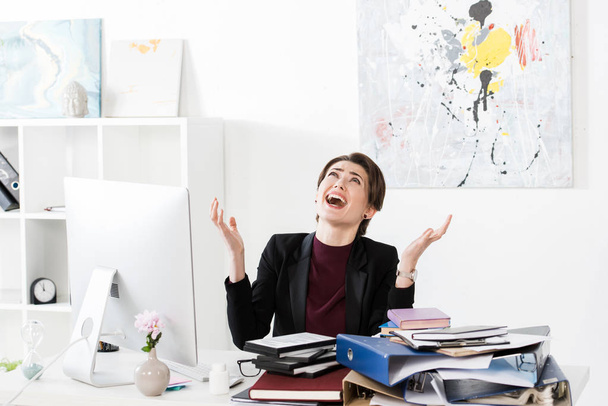 angry businesswoman gesturing, screaming and looking up in office - Фото, изображение