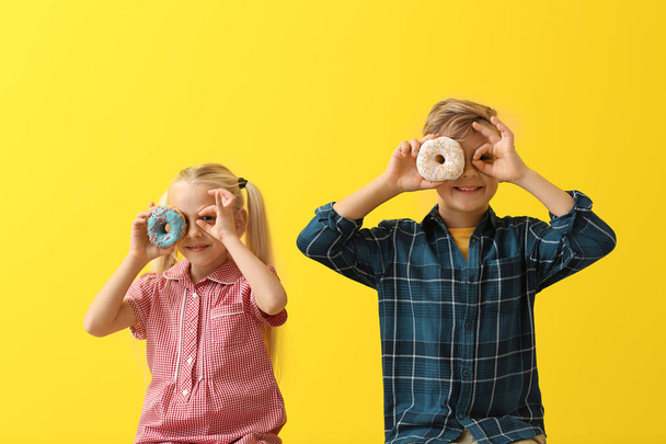 niedliche kleine Kinder mit Donut auf farbigem Hintergrund - Foto, Bild