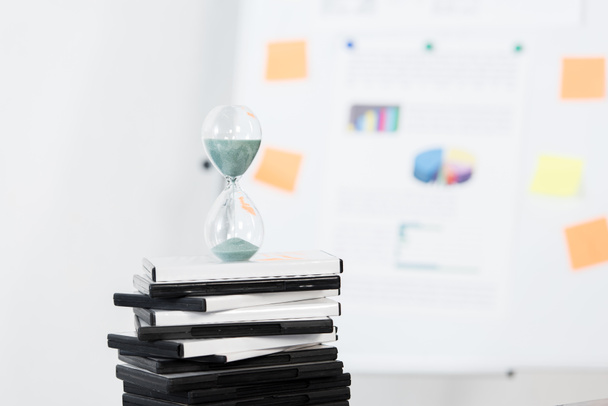 hourglass on stack of DVDs in light business office - Foto, Imagen