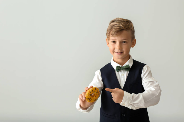 Cute little boy with donut on light background - Foto, Imagen