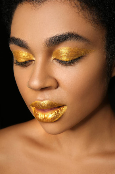 afrikanisch-amerikanische Frau mit goldenem Make-up auf schwarzem Hintergrund, Nahaufnahme - Foto, Bild