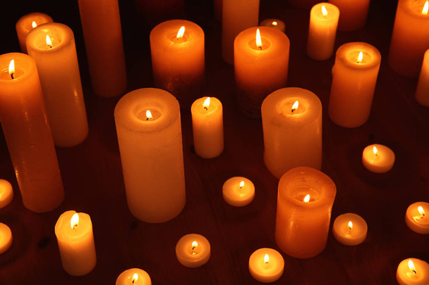 Many burning candles on table in darkness - Foto, Imagem