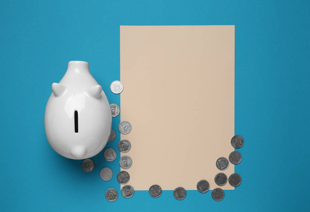 Piggy bank, moedas e folha de papel em branco no fundo de cor. Conceito de poupança
 - Foto, Imagem