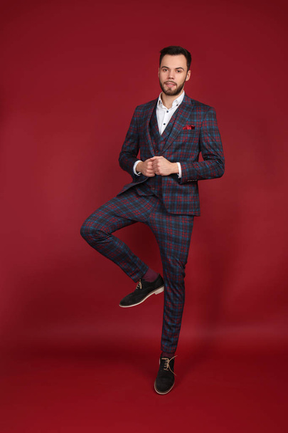 Jumping fashionable man in stylish suit on color background - Фото, изображение