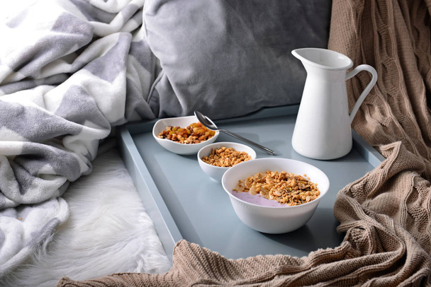 Чаши с вкусной мюсли и йогуртом на кровати
 - Фото, изображение