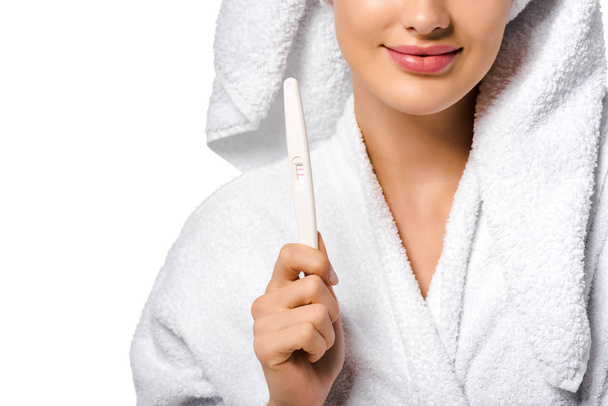 przycięte widzenia dziewczyna w szlafrok uśmiechający się i test ciążowy wyświetlone na białym tle - Zdjęcie, obraz