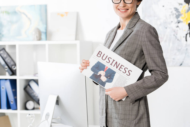 abgeschnittenes Bild einer lächelnden Geschäftsfrau mit Zeitung im Amt - Foto, Bild