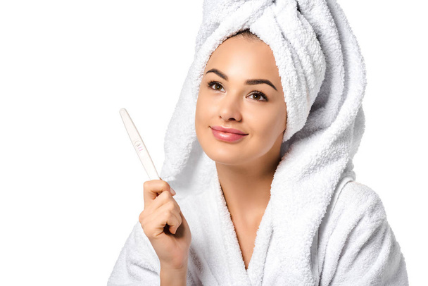 dreamy girl in bathrobe holding pregnancy test isolated on white - Foto, Imagem