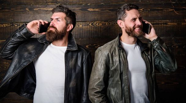 Modern technology. Men with smartphones discuss business. Mobile conversation and connect. Business call. Men brutal bearded hipster in fashionable leather jackets use mobile phone. Online business - 写真・画像