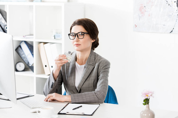 attractive businesswoman sniffing jar of perfume in office - Foto, Imagem