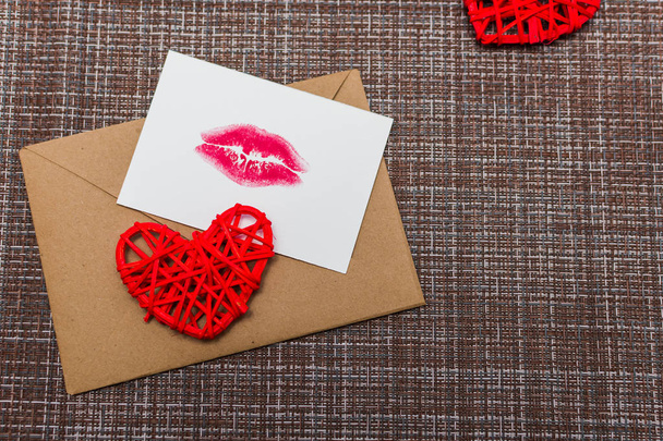 Sobre Kraft, corazones y tarjeta con una impresión de labios. el concepto del día de San Valentín
 - Foto, imagen
