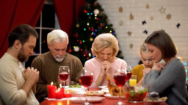 Traditional family praying before Christmas meal, belief in god, Christianity - Valokuva, kuva