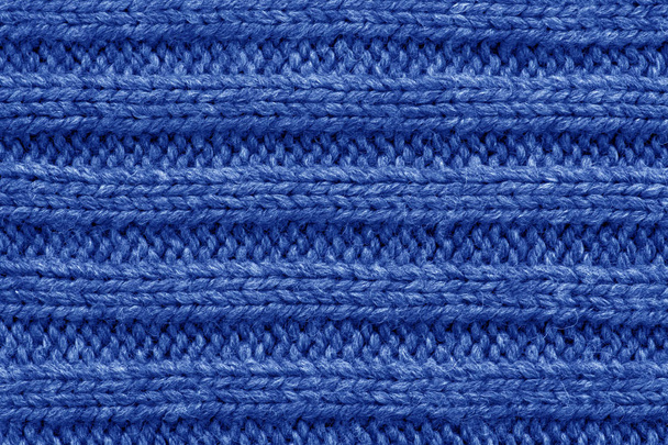 Gebreide patroon. Patroon stof gemaakt van wol. Achtergrond, kopie ruimte. Handgemaakte trui patroon, gebreid van wol patroon, blauwe achtergrond - Foto, afbeelding