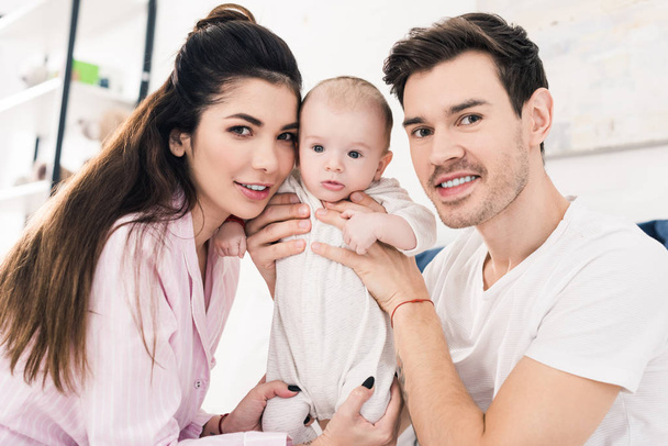 portrait of young parents with little son looking at camera at home - Photo, Image