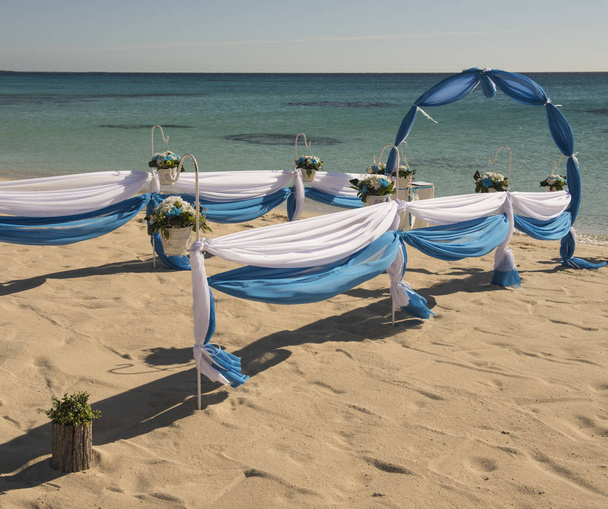Setup of wedding day marriage aisle with drapes and arch on sandy tropical beach paradise to open ocean background  - Photo, Image