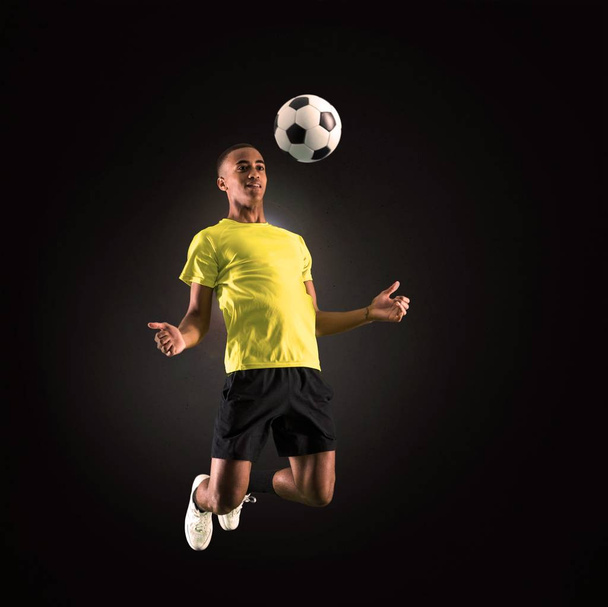Jogador de futebol homem com pele escura jogando no fundo escuro
 - Foto, Imagem