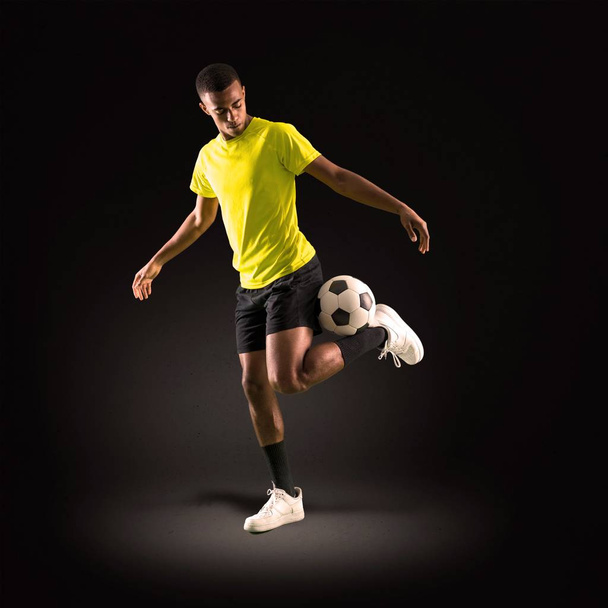 Άνθρωπος παίκτης ποδοσφαίρου με σκοτάδι εκδορά παίζοντας σε σκούρο φόντο - Φωτογραφία, εικόνα