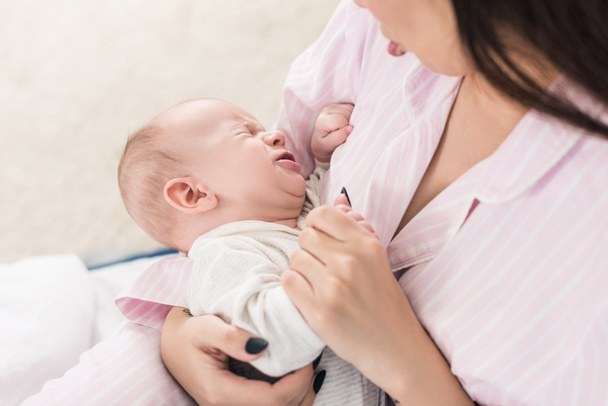 Anne küçük ağlayan bebek sakinleştirici kısmi görünümünü ellerinde - Fotoğraf, Görsel