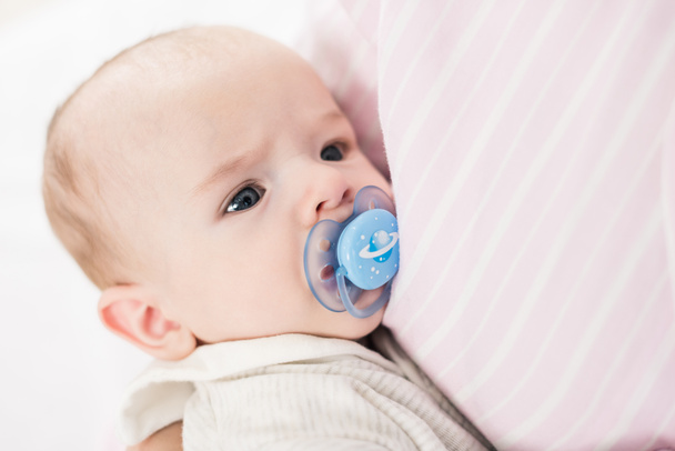 partial view of little baby with pacifier on mothers hands - Foto, Imagem