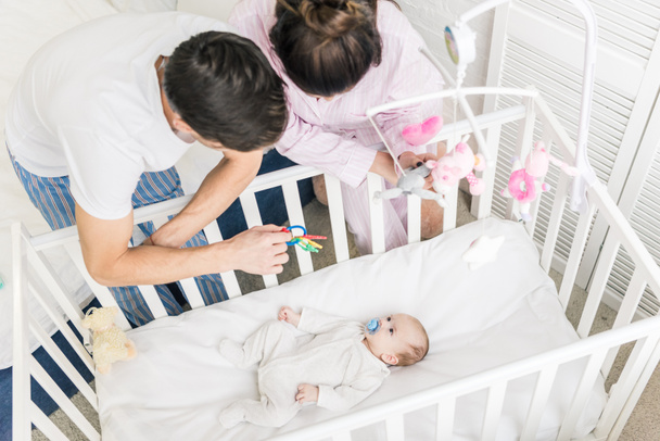 high angle view of young parents looking at baby in crib at home - Valokuva, kuva