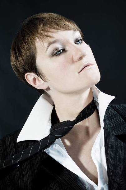 Woman with short hair cut wearing business suit takes off tie - Foto, imagen