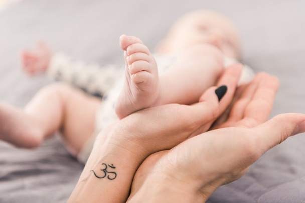 partial view of mother and father holding babys foot together - Фото, зображення