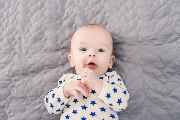 bovenaanzicht van schattige kleine baby liggend op grijze deken - Foto, afbeelding