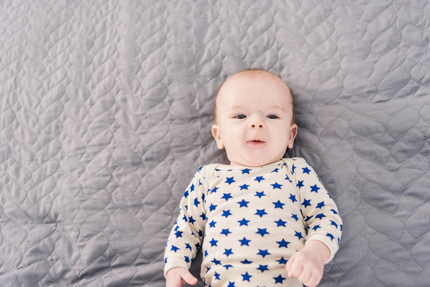 灰色の毛布の上に横たわる愛らしい赤ちゃんのオーバー ヘッド ビュー - 写真・画像