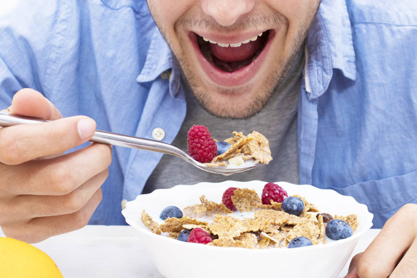 young man eating cereal with fruit - Photo, Image