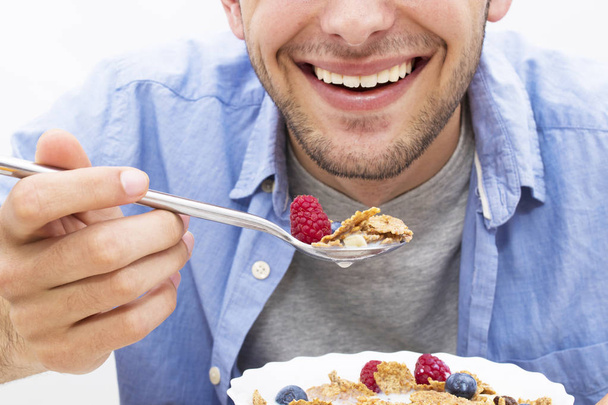 young man eating cereal with fruit - Foto, afbeelding